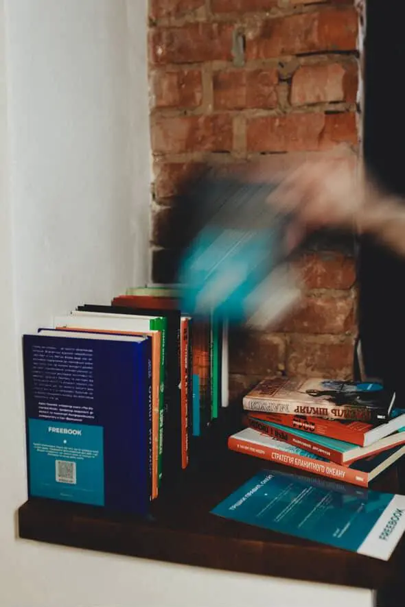 Людина бере книгу з полички